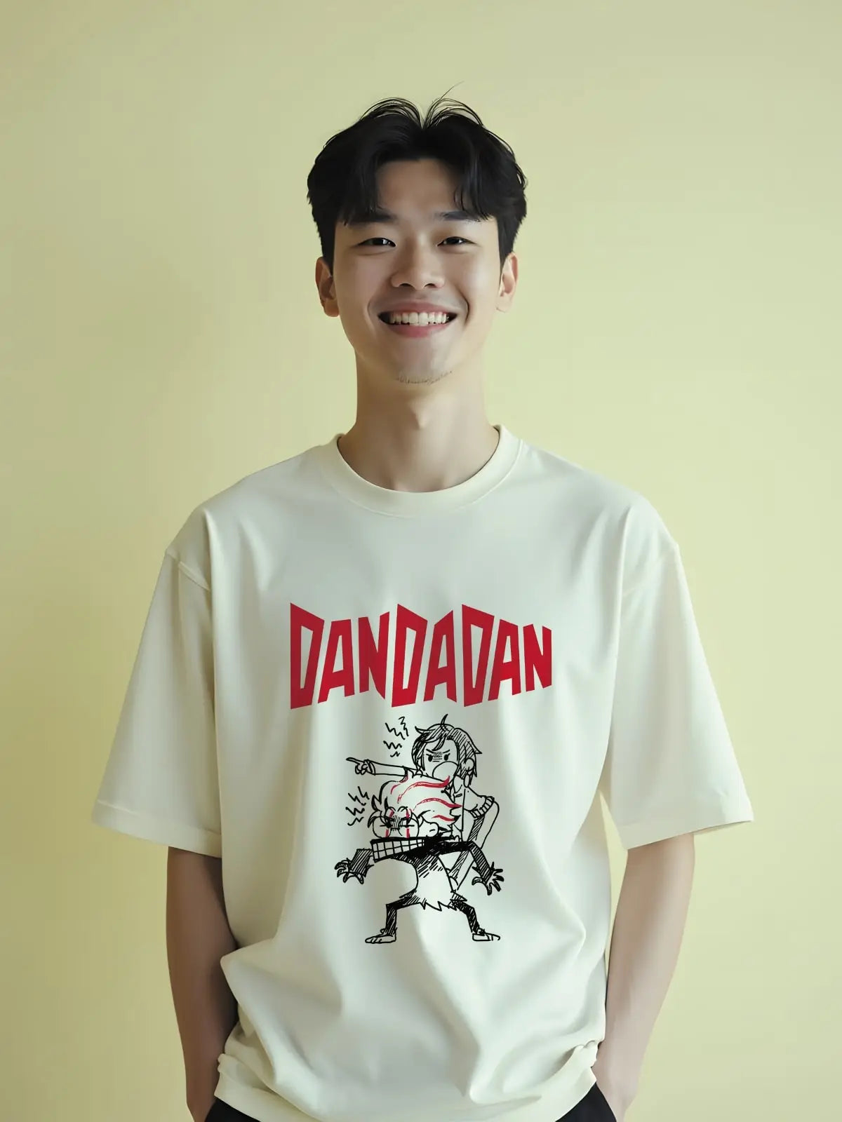Person wearing a white t-shirt with 'DANDADAN' graphic design on a yellow background