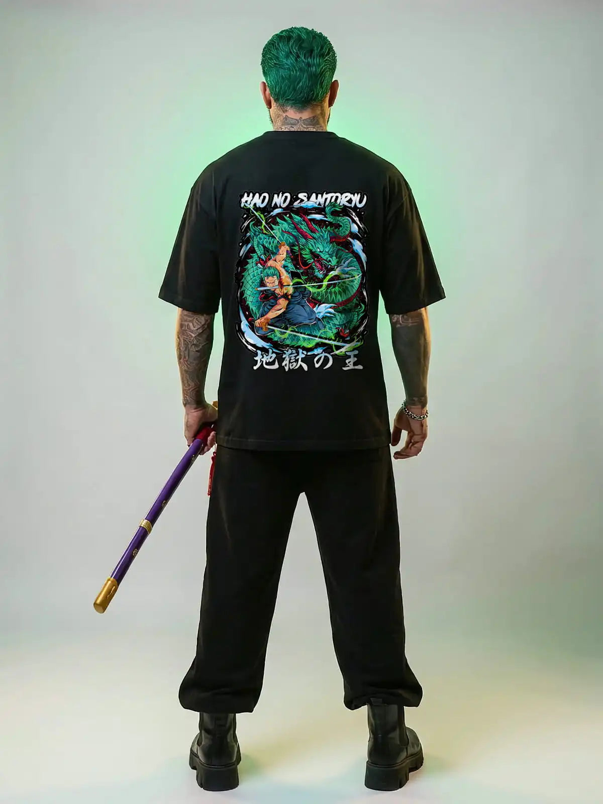 Person wearing a black t-shirt with a graphic design and text, holding a weapon, on a plain background.